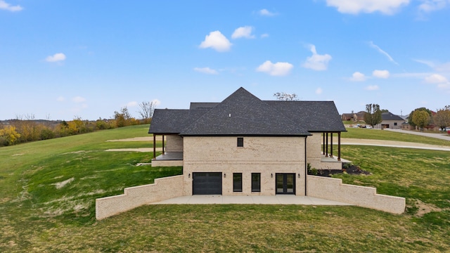 rear view of house with a yard, a garage, and a patio