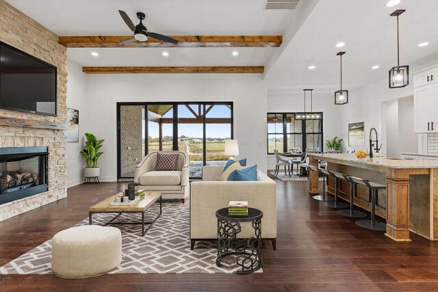 unfurnished living room with sink, dark hardwood / wood-style flooring, beamed ceiling, ceiling fan, and a fireplace