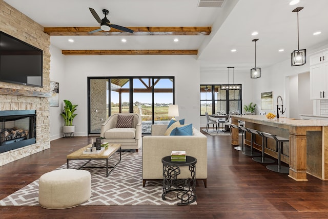 living room featuring sink, ceiling fan, dark hardwood / wood-style floors, a fireplace, and beamed ceiling