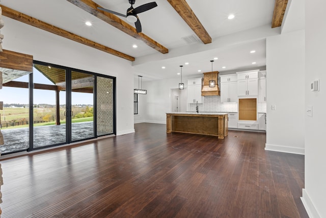 unfurnished living room with beamed ceiling, dark hardwood / wood-style floors, sink, and ceiling fan