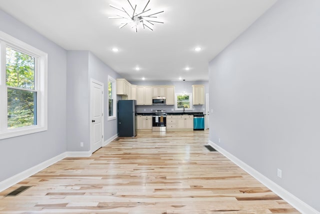 kitchen featuring appliances with stainless steel finishes, a notable chandelier, sink, and light hardwood / wood-style floors