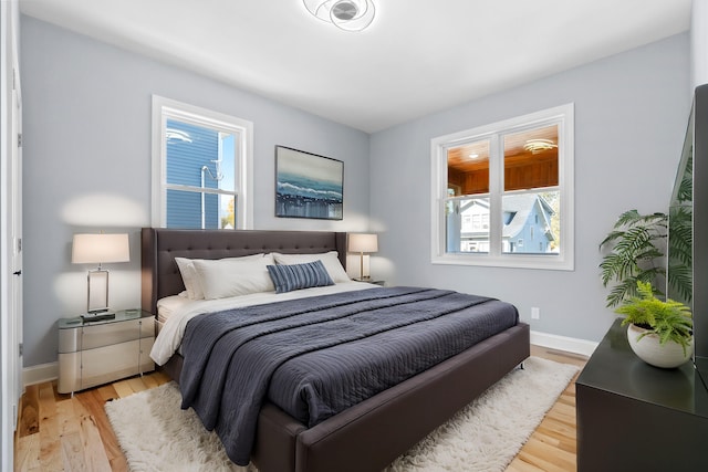 bedroom with light hardwood / wood-style floors and multiple windows