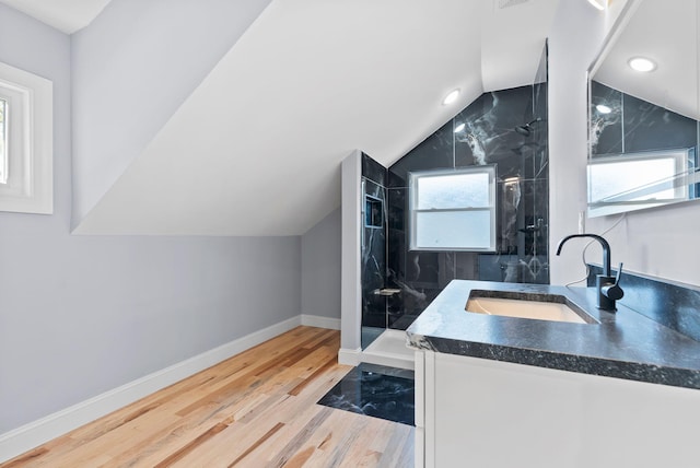 bathroom with a shower with door, vanity, hardwood / wood-style flooring, and lofted ceiling