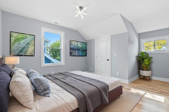 bedroom with vaulted ceiling, multiple windows, and light hardwood / wood-style floors