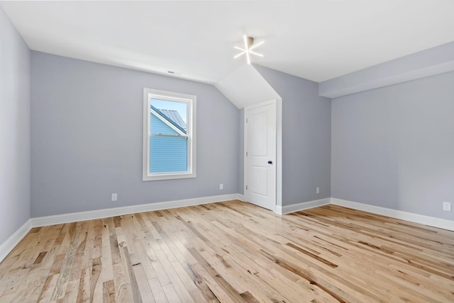 additional living space with light wood-type flooring and vaulted ceiling