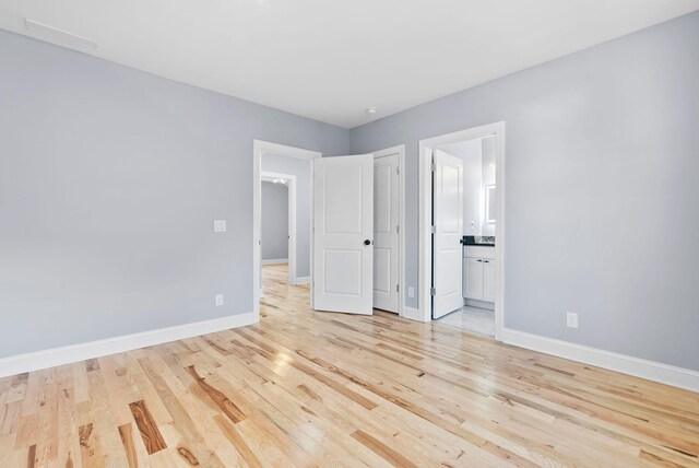 unfurnished bedroom featuring ensuite bath and light wood-type flooring