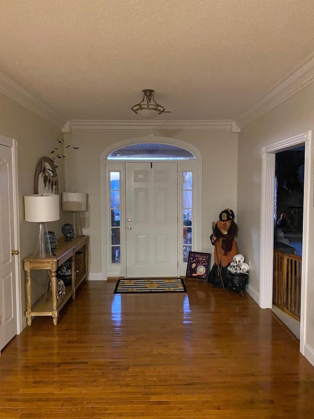 foyer entrance with a textured ceiling, dark hardwood / wood-style flooring, and ornamental molding