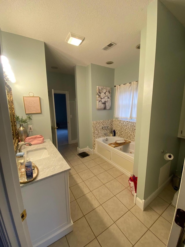 bathroom featuring tile patterned floors, a bathing tub, vanity, and a textured ceiling