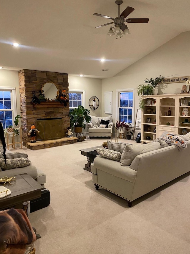 carpeted living room featuring a fireplace, vaulted ceiling, and ceiling fan