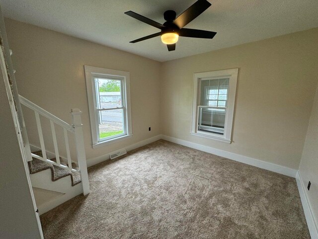 carpeted spare room with ceiling fan and a textured ceiling