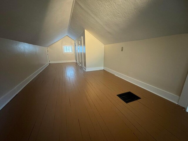 bonus room featuring lofted ceiling, a textured ceiling, and hardwood / wood-style flooring