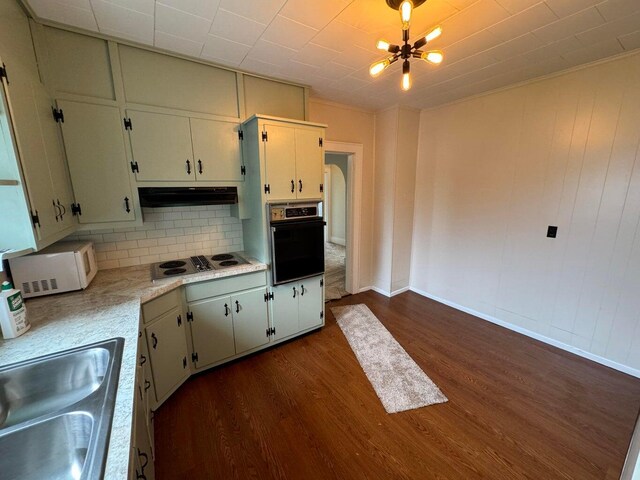 kitchen featuring decorative backsplash, dark hardwood / wood-style floors, sink, a chandelier, and white appliances