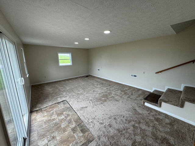 carpeted spare room featuring a textured ceiling