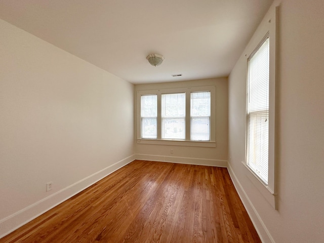 empty room featuring visible vents, baseboards, and wood finished floors
