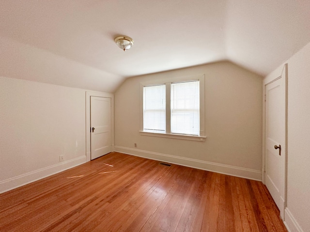 additional living space featuring visible vents, baseboards, vaulted ceiling, and light wood-type flooring