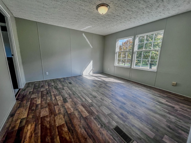 unfurnished room with dark hardwood / wood-style flooring and a textured ceiling