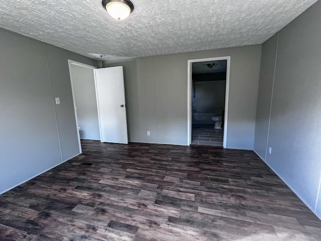 unfurnished room featuring dark hardwood / wood-style flooring and a textured ceiling