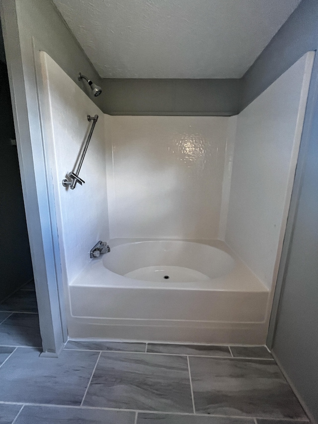 bathroom with shower / tub combination and a textured ceiling