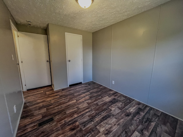 unfurnished bedroom featuring a textured ceiling and dark hardwood / wood-style floors