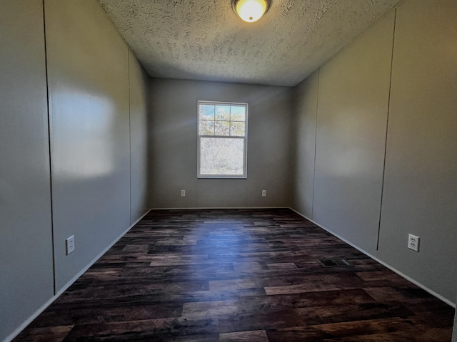 empty room with dark hardwood / wood-style flooring and a textured ceiling