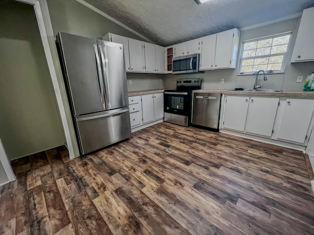 kitchen featuring stainless steel appliances, sink, a textured ceiling, white cabinets, and vaulted ceiling