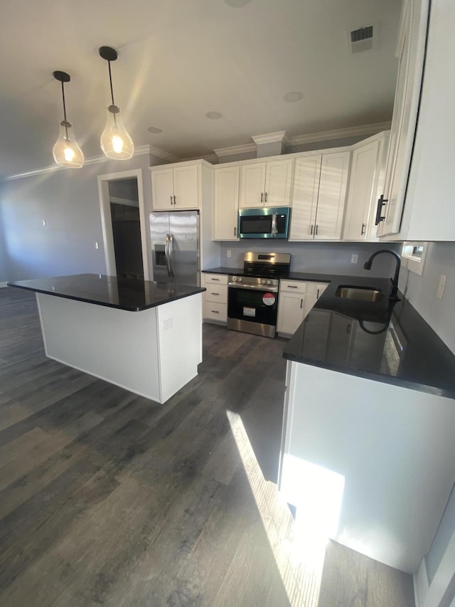 kitchen with appliances with stainless steel finishes, dark countertops, a sink, and white cabinets