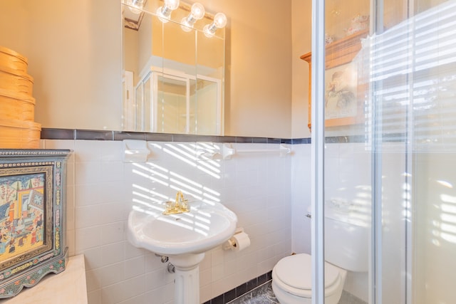 bathroom with toilet, tile walls, and a shower with door