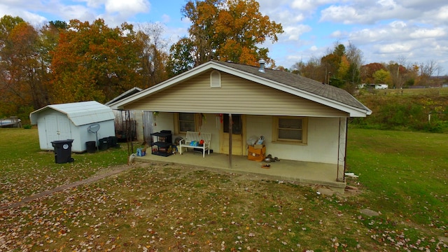 back of house with a shed and a lawn