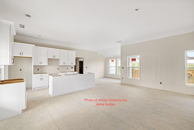 kitchen with a wealth of natural light, a kitchen island, and white cabinets