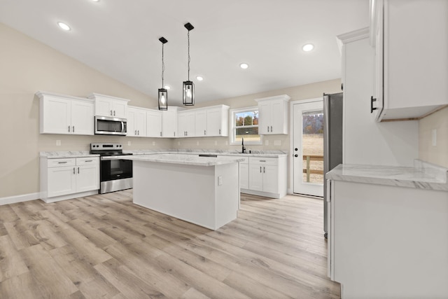 kitchen with stainless steel appliances, white cabinets, a sink, a kitchen island, and light wood-type flooring