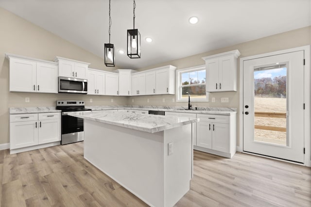 kitchen featuring lofted ceiling, stainless steel appliances, a sink, white cabinets, and a center island