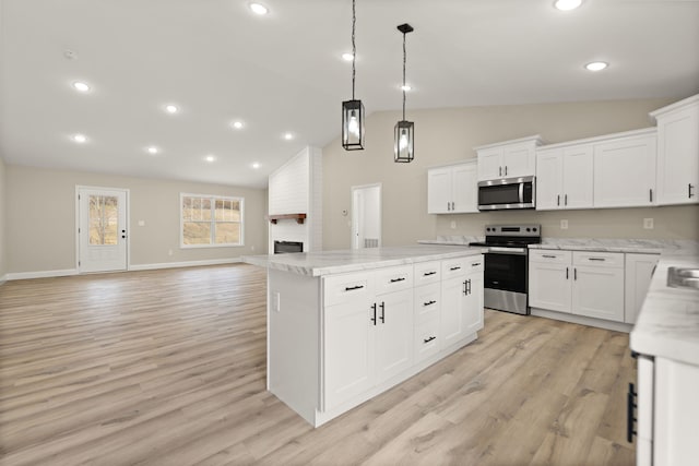 kitchen with stainless steel appliances, light wood-style floors, a brick fireplace, and a kitchen island