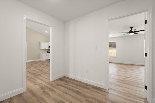 spare room featuring light wood-type flooring, ceiling fan, and baseboards