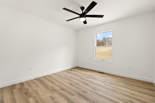 empty room with light wood-style floors, visible vents, baseboards, and a ceiling fan