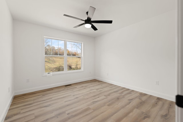 empty room featuring light wood-style flooring, visible vents, baseboards, and a ceiling fan