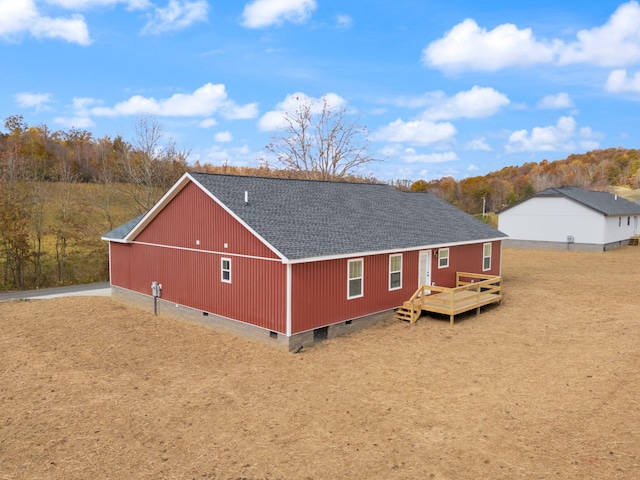 rear view of property featuring an outbuilding, roof with shingles, crawl space, a garage, and a pole building