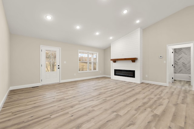 unfurnished living room featuring lofted ceiling, recessed lighting, a large fireplace, light wood-type flooring, and baseboards