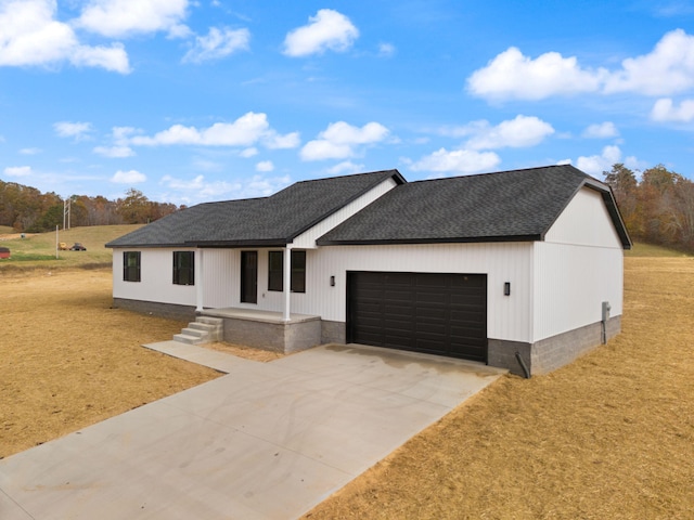 view of front of home with driveway, an attached garage, a front lawn, and a shingled roof