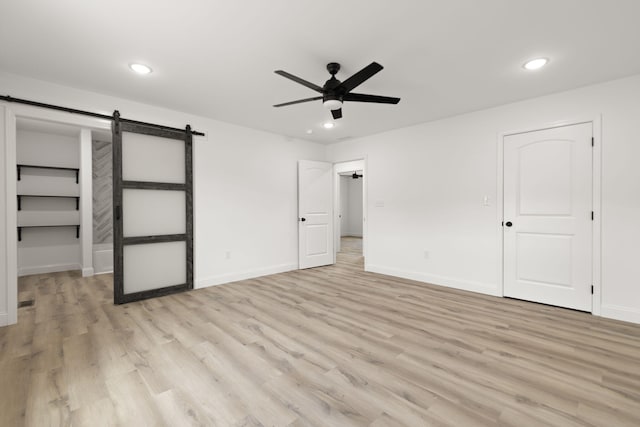 unfurnished bedroom featuring recessed lighting, light wood finished floors, and a barn door