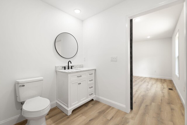 bathroom with vanity, wood finished floors, toilet, and baseboards