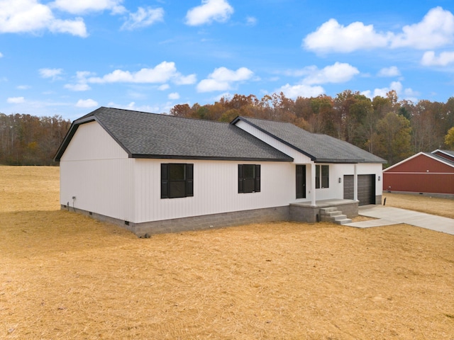 exterior space featuring a garage, driveway, crawl space, a lawn, and roof with shingles