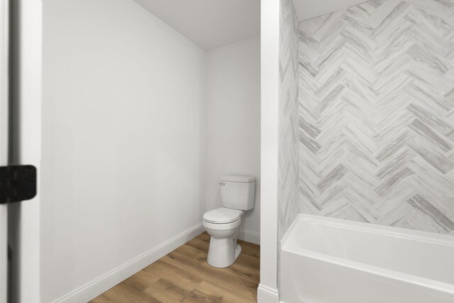 bathroom with toilet, baseboards, and wood finished floors