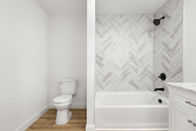 bathroom featuring toilet, wood finished floors, vanity, baseboards, and shower / washtub combination