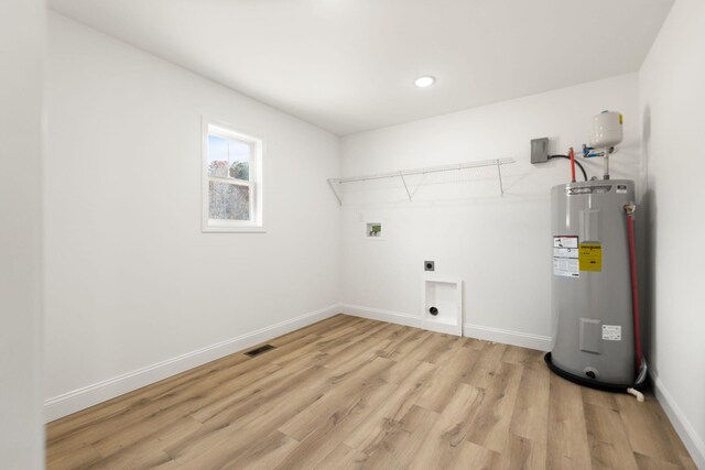 clothes washing area featuring hookup for a washing machine, electric water heater, electric dryer hookup, light wood-type flooring, and laundry area