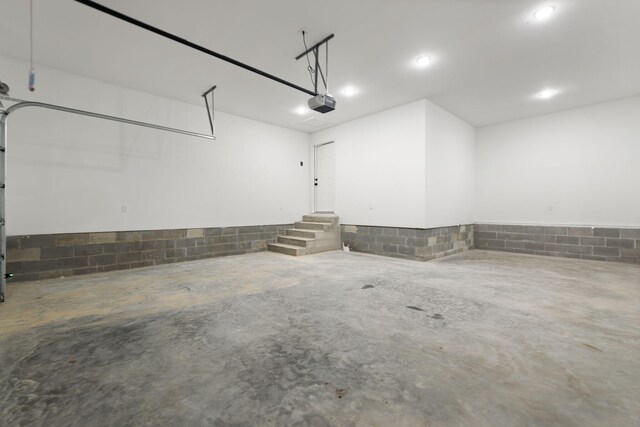 garage with concrete block wall and a garage door opener