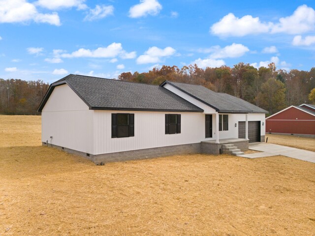 exterior space with a garage, a shingled roof, concrete driveway, a yard, and crawl space