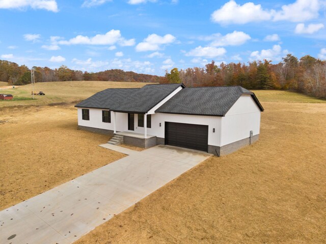 view of front of house featuring driveway, a shingled roof, and an attached garage