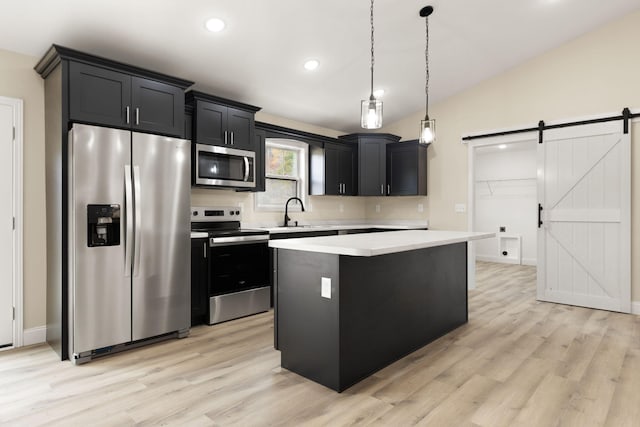 kitchen featuring a barn door, lofted ceiling, appliances with stainless steel finishes, light countertops, and dark cabinetry