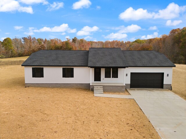 modern farmhouse featuring a garage, driveway, and roof with shingles