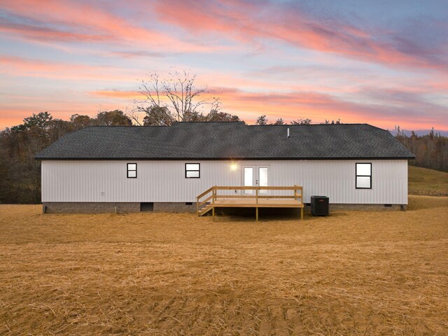 back of property at dusk featuring crawl space, roof with shingles, a wooden deck, and french doors